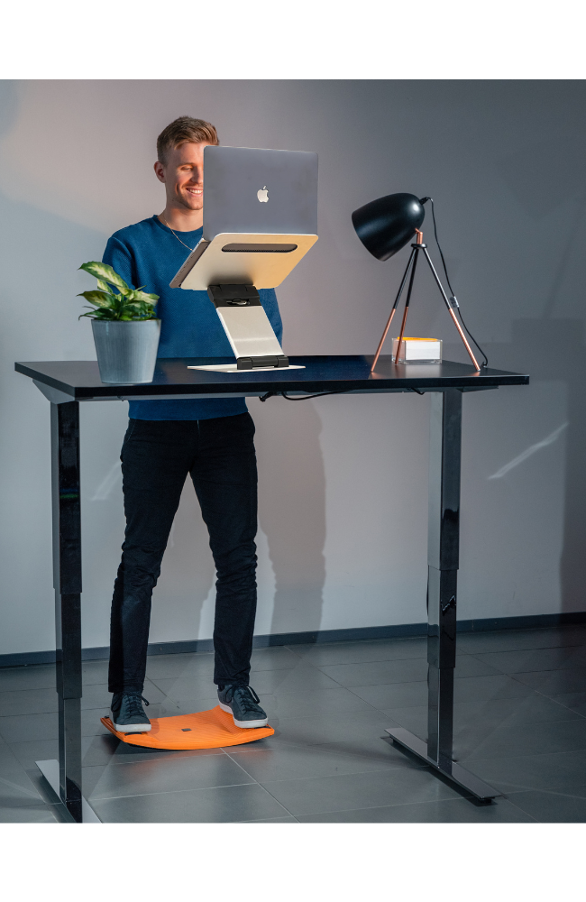 Man standing at his desk using the Gymba Board and Laptop Tower Stand